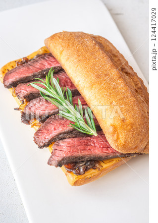 Grilled ciabatta sandwich with melted cheese, juicy steak, caramelized onions, and rosemary Grilled ciabatta sandwich with melted cheese, juicy steak, caramelized onions, and rosemary 124417029