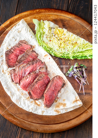 Sliced medium-rare beef steak with tortilla and crisp nappa cabbage wedge 124417043