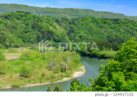 新緑のなかをコトコト走る飯山線の気動車を矢垂大橋から遠望する 124417132