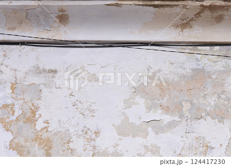 Aged wall with peeling paint and an exposed wire running horizontally across it Aged wall with peeling paint and an exposed wire running horizontally across it 124417230