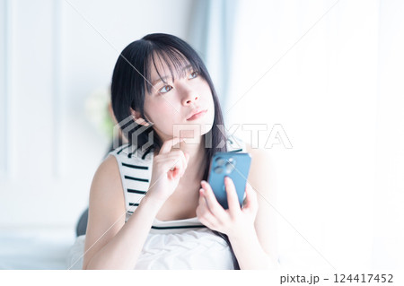 スマホを手に検討する若い女性 124417452