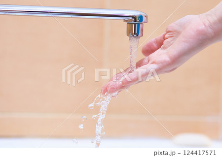 A woman's hand under the running water from the tap 124417571