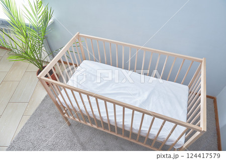 Baby bed top view. A bright room green potted flower and a carpeted floor. Baby bed top view. A bright room green potted flower and a carpeted floor. 124417579