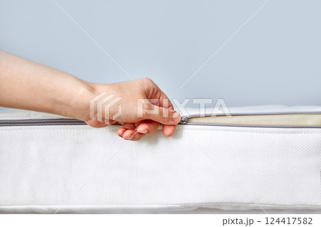 Orthopedic mattress with removable cover. Hand unzips the zipper close-up. Copy space 124417582