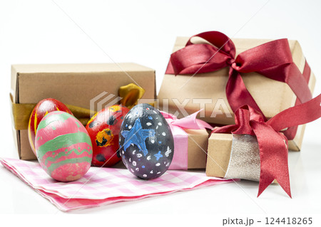 Colorful decorated easter eggs with gift boxes on a checkered square cloth isolated over a white background. Concept of celebrating the easter holiday 124418265