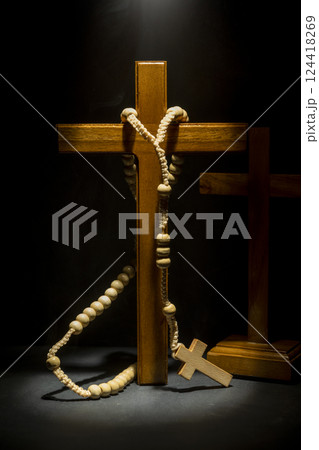 Wooden Christian cross and rosary beads on dark background. Light effect. Symbol of religious and worship in God. Concept of Hope, faith, and religion 124418269