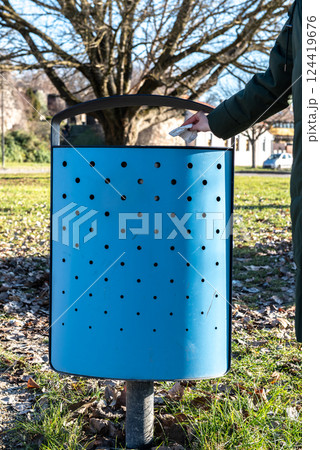 female hand throws a tissue into a blue street trash can female hand throws a tissue into a blue street trash can 124419676
