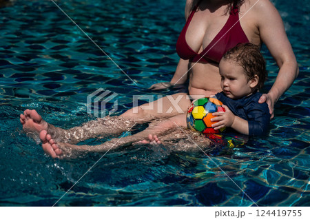 A Caucasian woman and her one-year-old son swim in a pool. 124419755