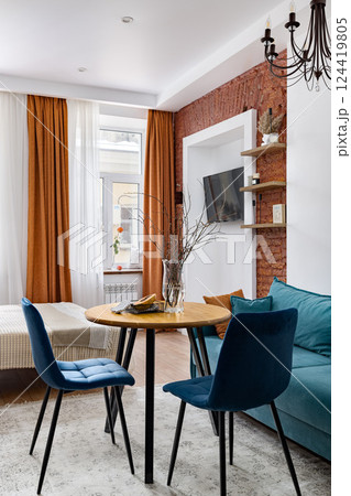 An Elegant Modern Living Room Featuring a Stylish Blue Sofa and a Beautiful Wooden Dining Table 124419805