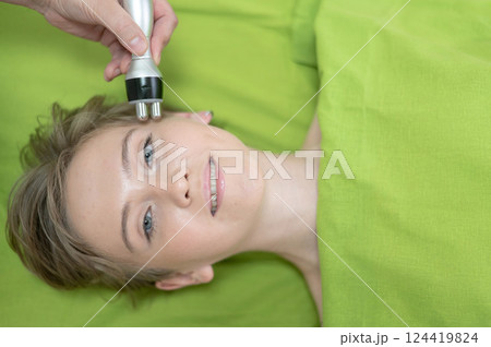 Top view of Caucasian woman undergoing radio wave RF lifting procedure in beauty salon.  124419824