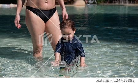 Caucasian one year old boy playing ball with mother in pool.  124419885