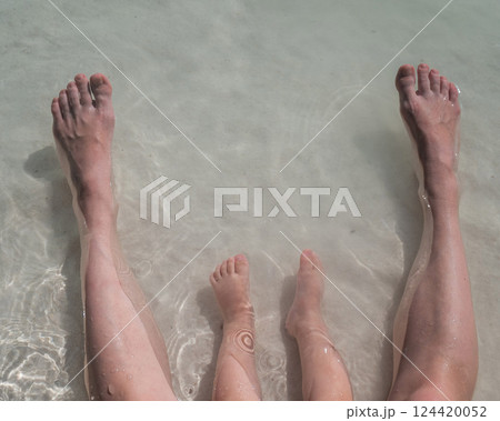 Top view of the legs of a one year old boy and his mother on the seashore.  124420052