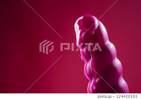 Lube pouring on pink dildo on pink background. Lube pouring on pink dildo on pink background. 124420101