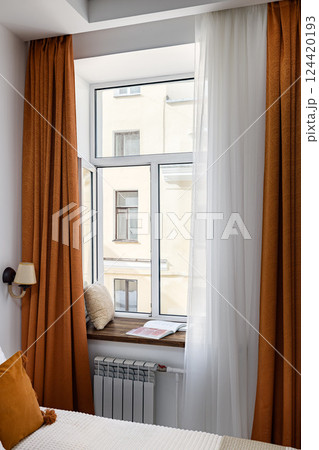 A stylish bedroom window adorned with elegant curtains and cozy decor creates a warm atmosphere 124420193
