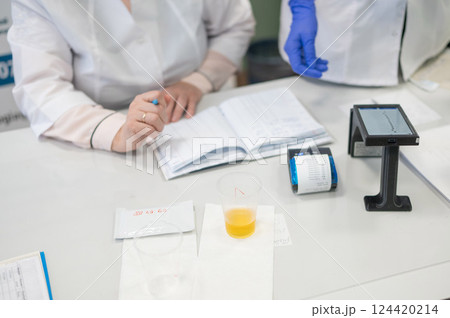 A narcologist tests urine for drugs using an electronic device.  124420214