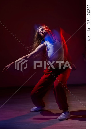 A young woman dances contemporary dances in blue and red light. Long exposure. Vertical photo.  124420292
