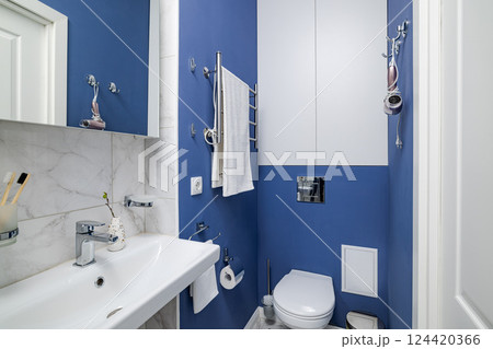 A beautifully designed modern compact bathroom showcasing blue accents alongside elegant fixtures A beautifully designed modern compact bathroom showcasing blue accents alongside elegant fixtures 124420366