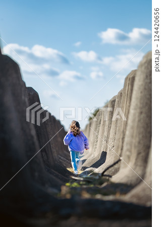 テトラポットの間を走る女の子 124420656
