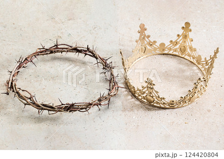 A crown of thorns lies beside an ornate golden crown 124420804