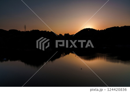 湖面を吹き渡る風 　2025年春奈良布目ダムにて　山際に沈む夕日と黄金色に染まる空と湖面① 124420836