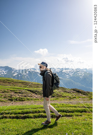A tourist walks along a green mountain trail at summer day. A tourist walks along a green mountain trail at summer day. 124420863