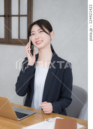 オフィスで働く若いビジネスウーマン　スマホで通話する	縦 124421422