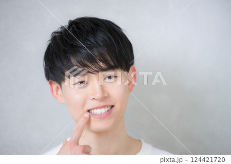 歯並びを指差す若い20代の男性 ホワイトニングや矯正のイメージ 歯並びを指差す若い20代の男性 ホワイトニングや矯正のイメージ 124421720