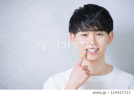 歯並びを指差す若い20代の男性　ホワイトニングや矯正のイメージ 124421721