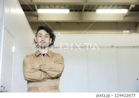 倉庫の中を歩くつなぎの男性 倉庫の中を歩くつなぎの男性 124422677