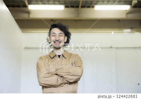 倉庫の中を歩くつなぎの男性 124422681