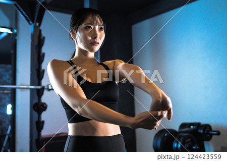 運動前に手首のストレッチをする、ジムで体を鍛えるかっこいい女性　準備運動筋トレ女子　トリミングアップ 124423559