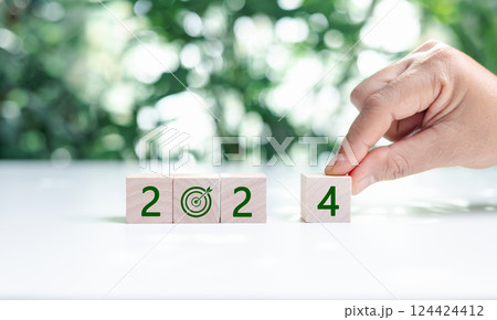 2024 numbers and earth care symbol on circle eco wooden blocks on wood table, green leaves background. Happy new year 2024 with the world care. Green environmental sustainability concepts. 124424412
