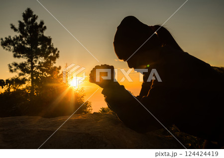 Silhouette of woman kneeling down praying for worship God at sky background. Christians pray to jesus christ for calmness. In morning people got to a quiet place and prayed. copy space. 124424419