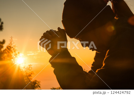 Woman kneeling to pray on Easter Day. Silhouette of prayer woman kneeling and praying over autumn sunset background. Forgive concept. praying over beautiful sunrise background Woman kneeling to pray on Easter Day. Silhouette of prayer woman kneeling and praying over autumn sunset background. Forgive concept. praying over beautiful sunrise background 124424792