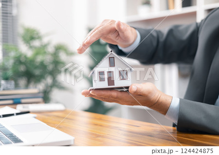 Insurance house concept. The insurance agent presents the hands protection model house. Make a contract for hire purchase and sale of a house. home insurance contracts, home mortgage loan concepts. Insurance house concept. The insurance agent presents the hands protection model house. Make a contract for hire purchase and sale of a house. home insurance contracts, home mortgage loan concepts. 124424875
