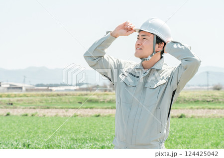 田舎の田んぼに立つ作業着姿のミドル世代の作業員・職人・現場監督 124425042