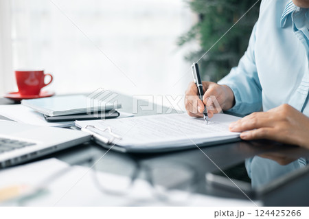 Close up businesswoman signing documents. Hand of woman write business document charts at office desk. Woman signing document, focus on female hand holding pen, putting signature at official paper. Close up businesswoman signing documents. Hand of woman write business document charts at office desk. Woman signing document, focus on female hand holding pen, putting signature at official paper. 124425266