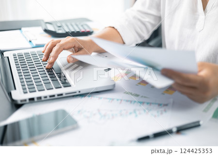Woman analyze document in her hands. Businesswoman analyst working at office on laptop while sitting at wooden table. Business financing accounting banking concept. finance accounting. 124425353