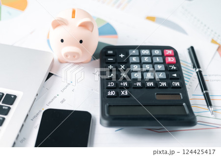 Piggy bank with business stuff, business and finance concept. calculators on financial statements, business chart showing financial success at the stock market 124425417