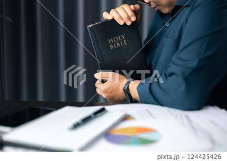 Businesswoman praying at work. Woman with hands clasped praying while sitting at desk in office. Contemplative prayer thinking in office. Hands folded in prayer gesture beg about something. 124425426