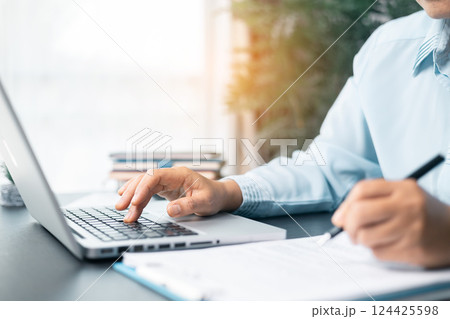 Business woman working on documents looking concentrated with briefcase on table. Businesswoman is deeply reviewing a financial report for a return on investment or investment risk analysis. 124425598