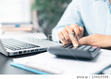 Business woman working on documents looking concentrated with briefcase on table. Businesswoman is deeply reviewing a financial report for a return on investment or investment risk analysis. Business woman working on documents looking concentrated with briefcase on table. Businesswoman is deeply reviewing a financial report for a return on investment or investment risk analysis. 124425599