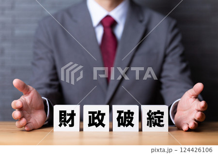 財政破綻のブロックとスーツを着たミドル男性ビジネスマン 財政破綻のブロックとスーツを着たミドル男性ビジネスマン 124426106