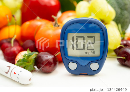 Asian hand holding digital glucose monitor measure with vegetable and fruit healthy food. Asian hand holding digital glucose monitor measure with vegetable and fruit healthy food. 124426449