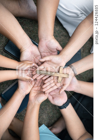 Group of Christian believers clasped hands in prayer, In the church, expressing their faith through worship and reverence for God, symbolized by the cross. Group christian pray concept. 124426885