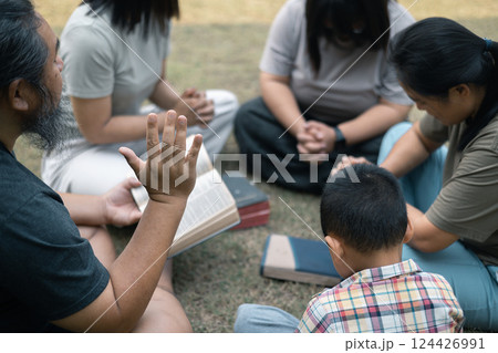 Young woman held her mother's hand in prayer, surrounded by their outdoor community, where love and family life flourished through shared moments of prayer and support. Group christian pray concept. Young woman held her mother's hand in prayer, surrounded by their outdoor community, where love and family life flourished through shared moments of prayer and support. Group christian pray concept. 124426991