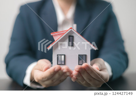 Home insurance concept. Homeowner entrusted the concept of protecting their property to the insurance agent's hand, ensuring their house and finances were secured through a mortgage insurance plan Home insurance concept. Homeowner entrusted the concept of protecting their property to the insurance agent's hand, ensuring their house and finances were secured through a mortgage insurance plan 124427149