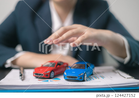 Car insurance concept. Agent negotiated a comprehensive insurance agreement for the auto business, covering all aspects of vehicle transport and automobile protection. Car insurance concept. Agent negotiated a comprehensive insurance agreement for the auto business, covering all aspects of vehicle transport and automobile protection. 124427152