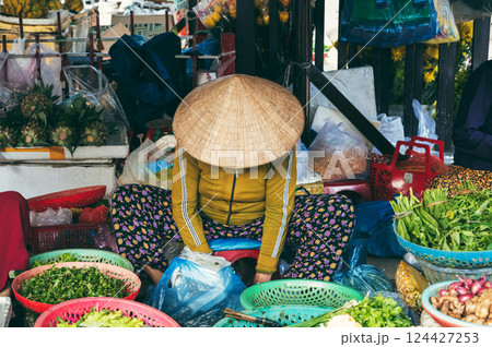 Vietnamese woman seller sells fruits and vegetables at food street Asian market in the old town in Hoi An in Vietnam in Asia 124427253