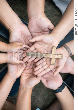 Group of Christian believers clasped hands in prayer, In the church, expressing their faith through worship and reverence for God, symbolized by the cross. Group christian pray concept. 124427387